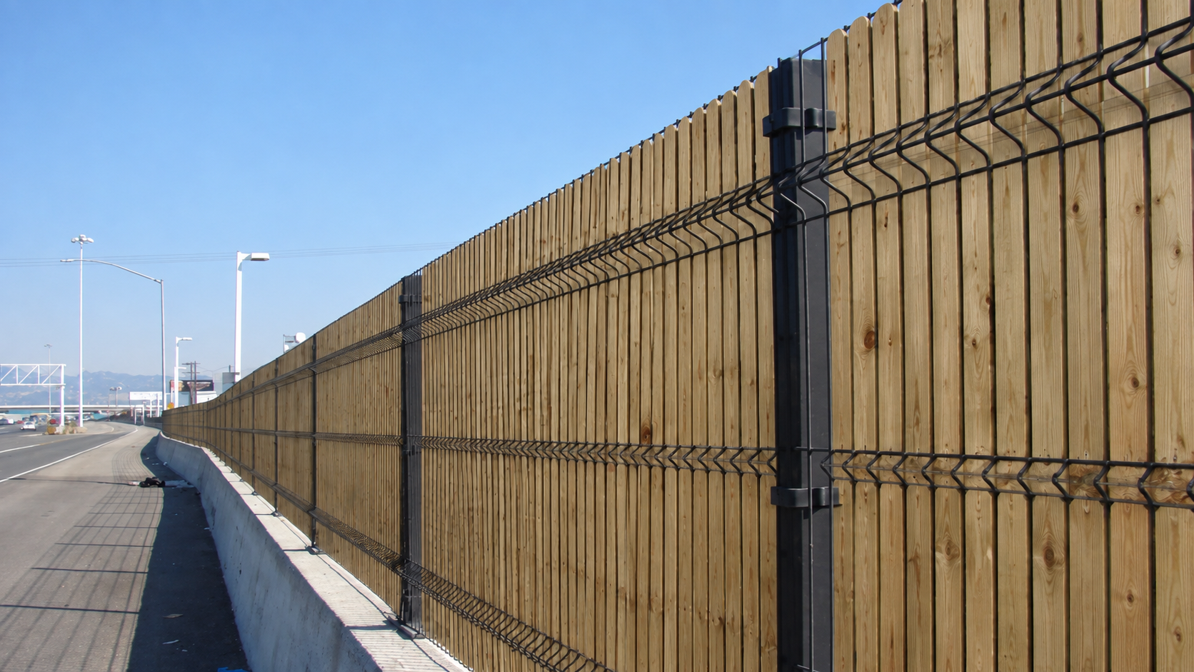 Duga panel ograda s drvenim letvicama duž ceste