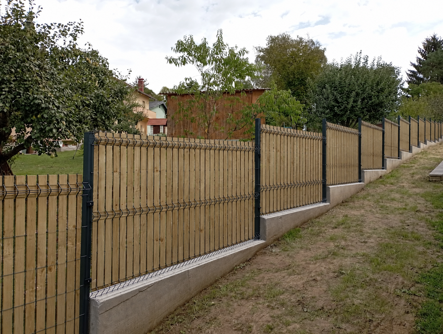 Ograda s drvenim letvicama u vrtu s raslinjem